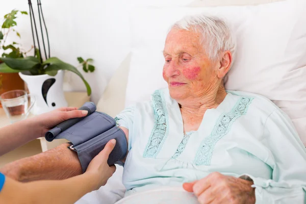 Elderly woman having her blood pressure measured
