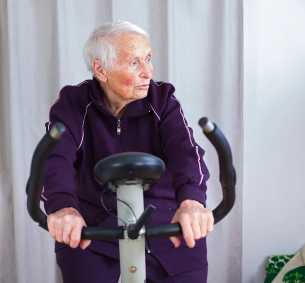 Elderly woman biking on an indoor bicycle