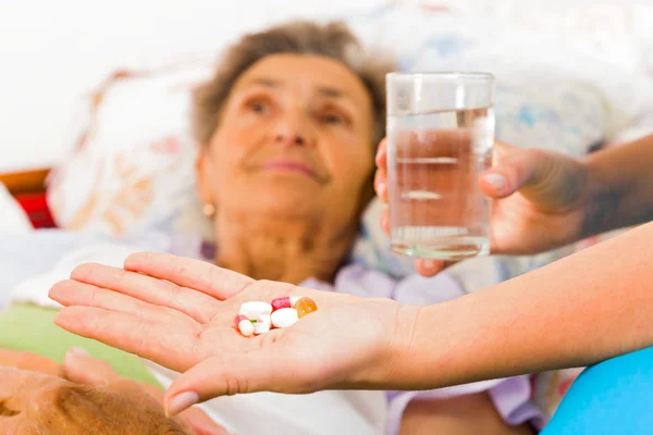 Nurse giving medication to elderly patient