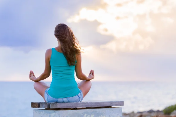 Lady in yoga meditation pose sitting on a bench