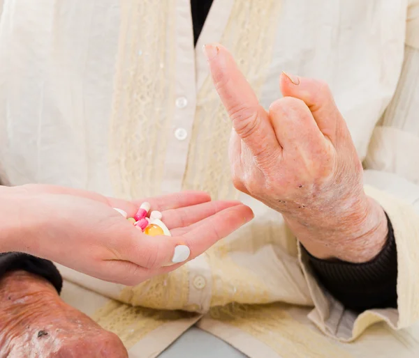 Elderly woman refusing medications with a rude gesture