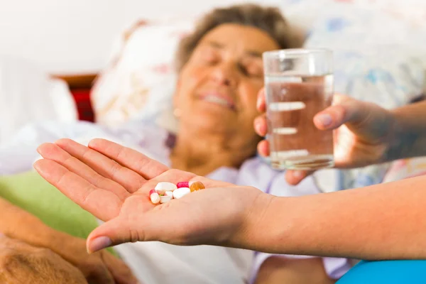 Elderly woman taking pills with water