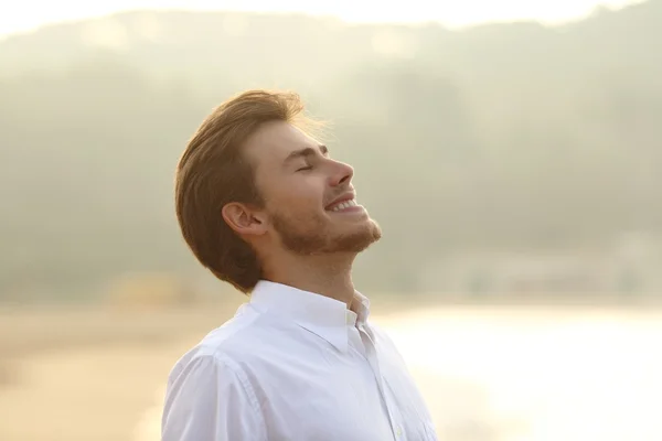 Happy man breathing deep on the beach in vacation