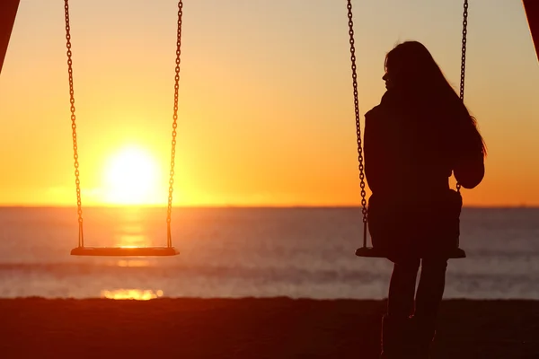 Single woman alone swinging on the beach