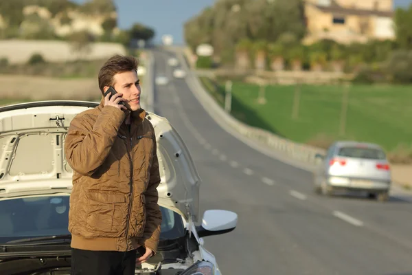 Happy man calling roadside assistance for his breakdown car