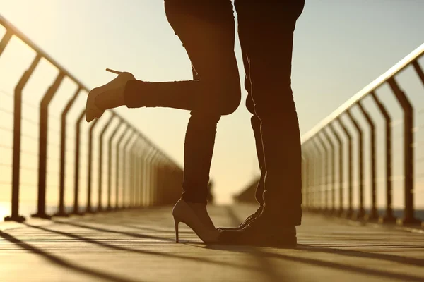 Couple legs silhouette hugging with love in a bridge