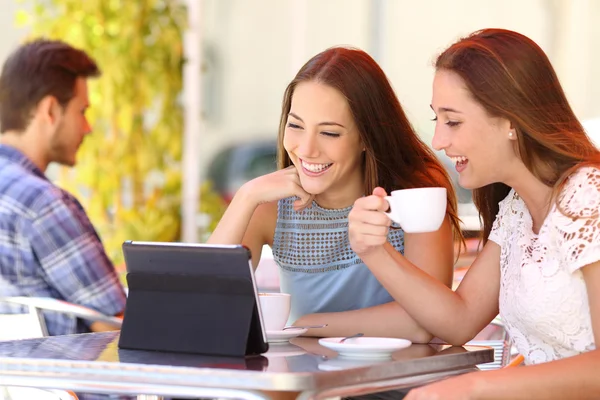 Two friends or sisters watching videos in a tablet