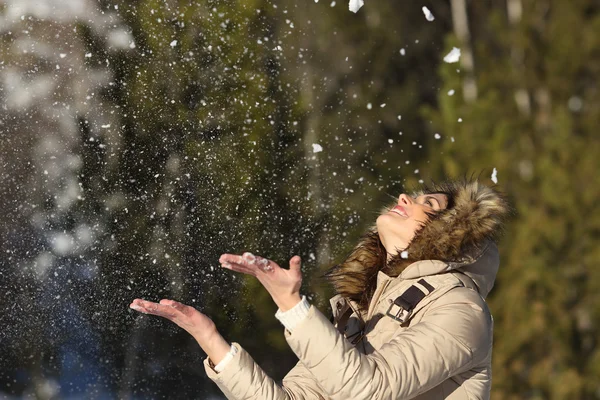 Happy girl throwing snow in the air on winter holdays