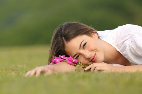 Relaxed woman resting on the green grass with flowers