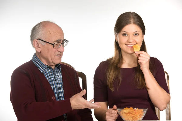 Old man and young woman eating chips