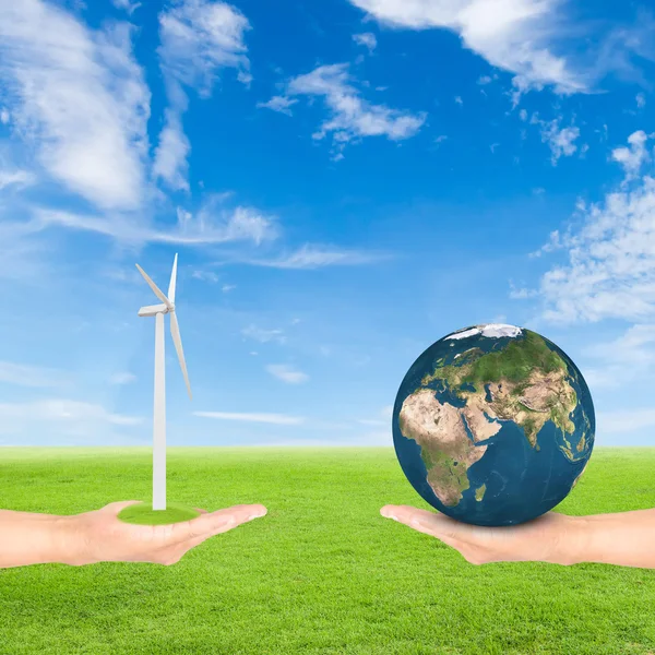 Hand holding wind turbine and earth