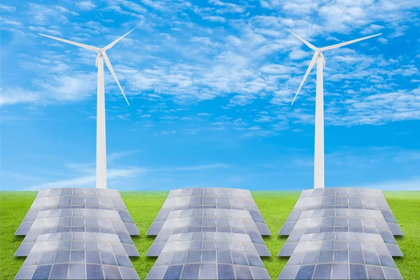 Solar panels and wind turbine on green grass field against blue