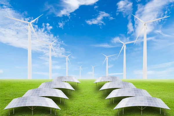 Solar panels and wind turbine on green grass field against blue