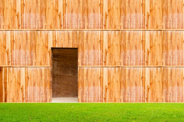 Wooden wall with door and grass floor in front off