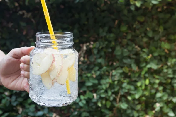 Hand hold glass of iced apple soda drink