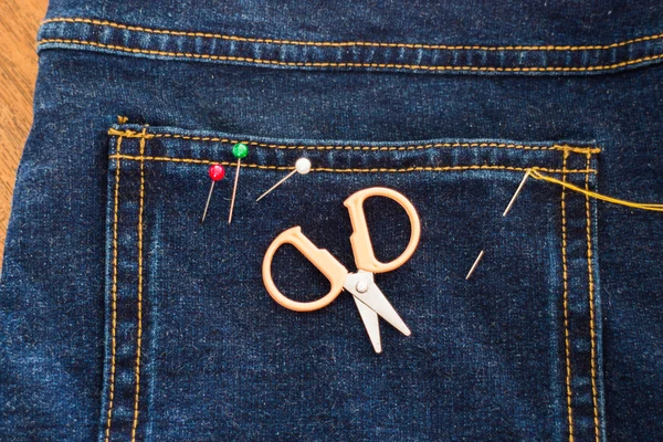 Needle with a thread through the jean