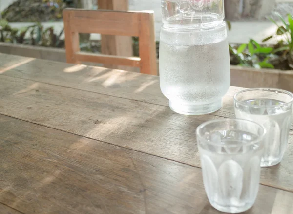 Double glasses of cold water on wooden table