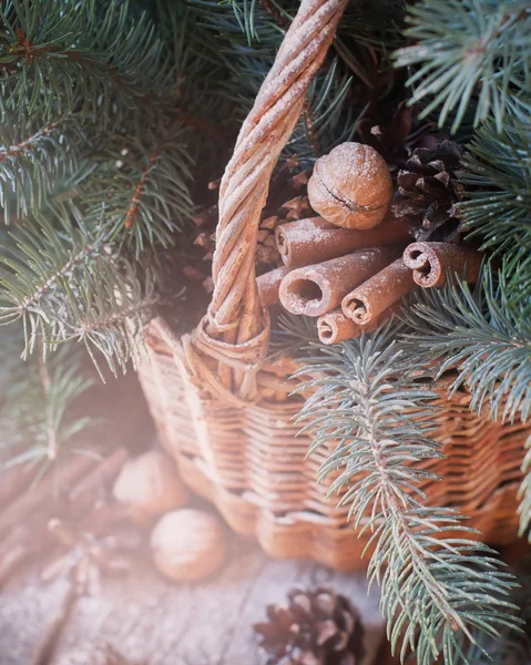 Natural Christmas Decor in a Basket. Nuts, Fir Tree, Cinnamon, Pine cones on Wooden Background