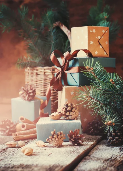 Christmas Gifts with Boxes, Coniferous, Basket, Cinnamon, Pine Cones, Wallnuts on Wooden Background. Vintage Toned