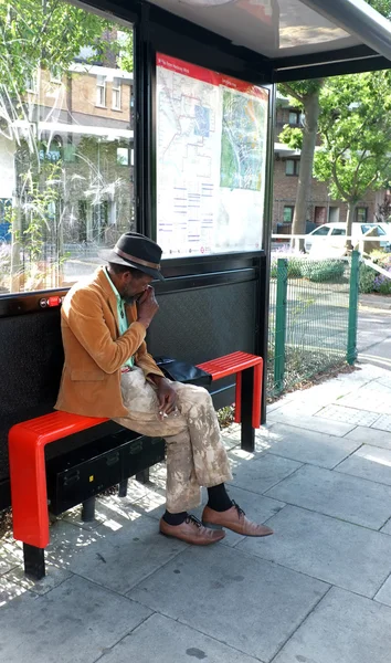 Elderly black man sitting at the bus stop