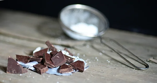 Broken chocolate bar and spices on wooden table