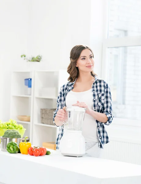 Pregnant woman cooking with blender.