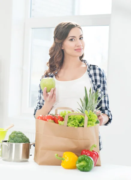 Pregnant woman in kitchen with apple