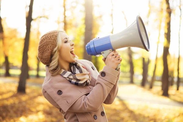 Woman yelling with loudspeaker in the autumn park