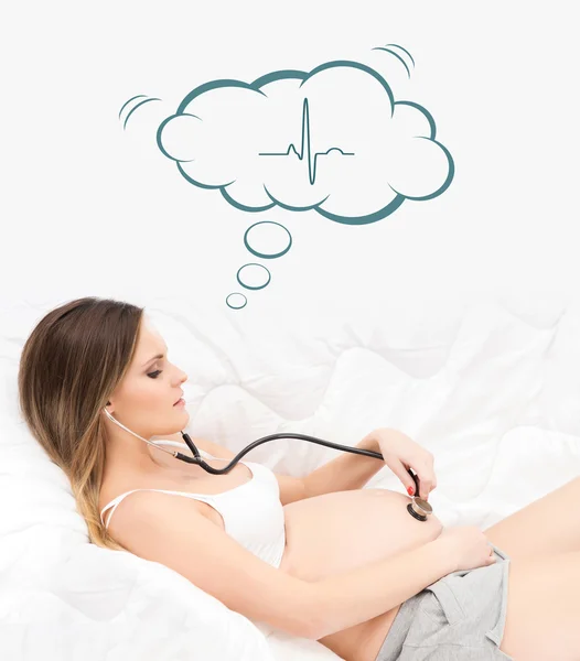 Pregnant woman listening to her belly with a stethoscope
