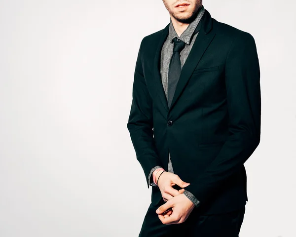 A young man in a fashionable suit posing. Part of body. Indoor. Warm color.