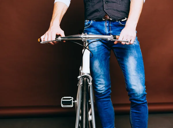 Indoor portrait of young fashion handsome hipster man with vintage bike. Warm color. Close up.