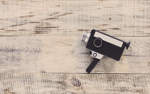 Classic vintage old 8mm movie camera on old wooden boards. Hipster style. Top view with copy space. Free space for text.