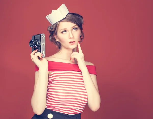Beautiful pin-up girl holding in his hand a vintage camera