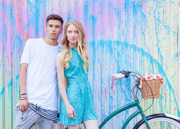 Young happy hipster couple in love meet each other and dating whis vintage bicycle. Pretty blonde caucasian woman with her hispanic boyfriend posing outdoor in summer