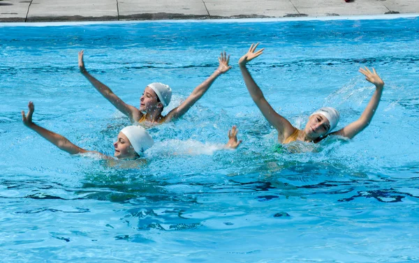 Group of girls in a pool practicing synchronized swimming
