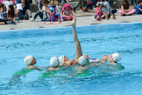 Group of girls in a pool practicing synchronized swimming