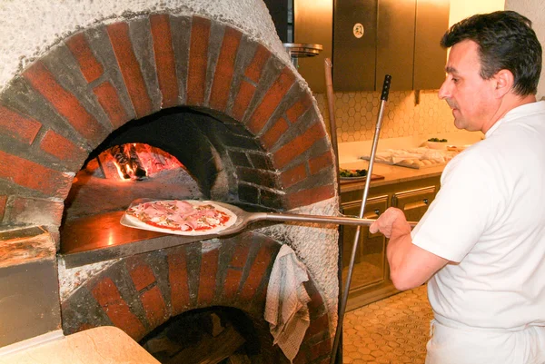 Pizza maker bake a pizza in the wood oven