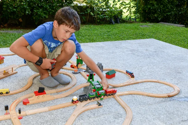 Boy playing with a wooden train set