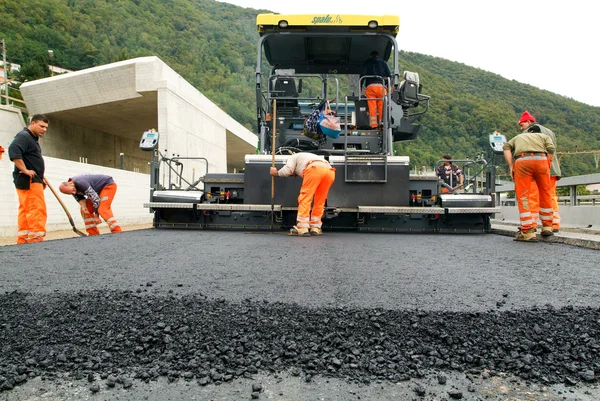 Workers and vehicles during the asphalting of the highway