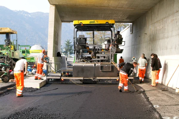 Workers and vehicles during the asphalting of the highway