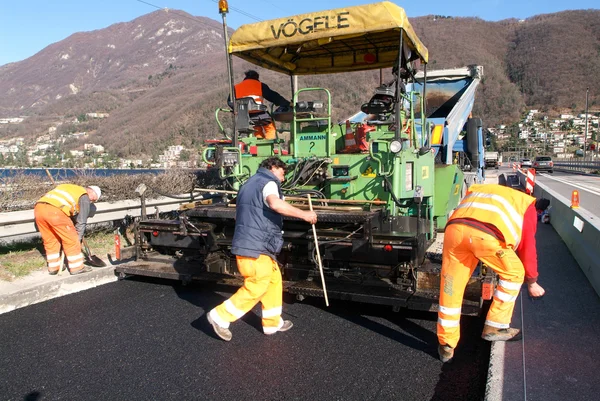 Workers and vehicles during the asphalting of the highway