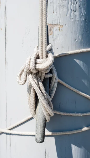 Rope tied on cleat casting shadow on white mast