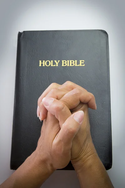 Praying hands over holy bible