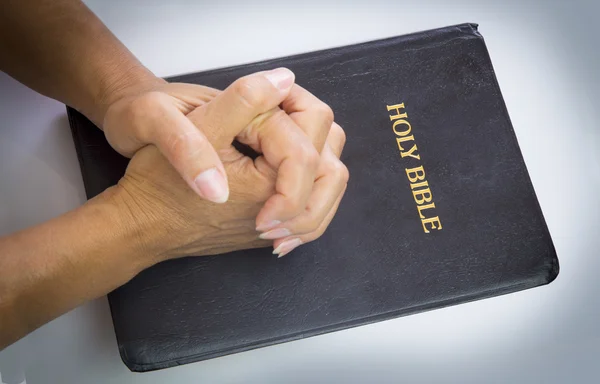 Praying hands over holy bible