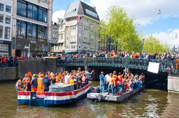 AMSTERDAM, NETHERLANDS-APRIL 27: People on Party Boat with crowd of people on the bridge on King\'s Day on April 27,2015.
