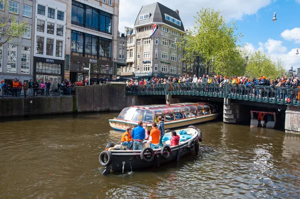 AMSTERDAM-APRIL 27: Boat paty on the Singel canal, crowd of people on the bridge on King\'s Day on April 27,2015.