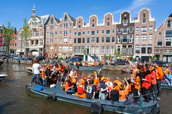 AMSTERDAM-APRIL 27: Crowd of people and tourists on the boats participate in celebrating King\'s Day through Singel canal on April 27,2015.