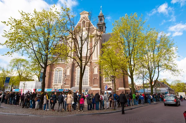 People stand in a queue to visit the Anne Frank House Museum in Amsterdam.