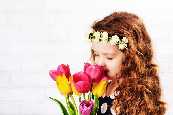 Sweet child Girl smelling a bouquet of tulips.