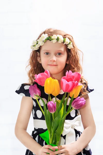Sweet child with bouquet of tulips.